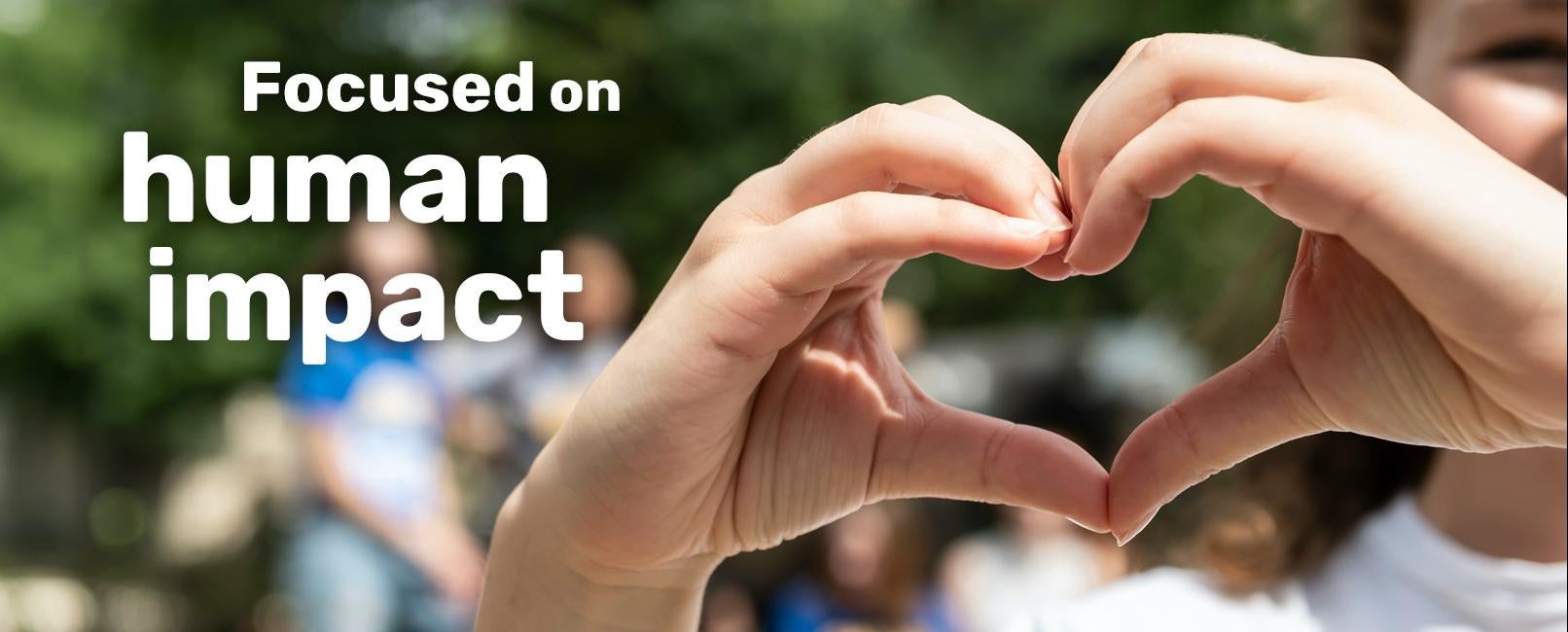 Hands coming together to form heart: Focused on human impact text over image